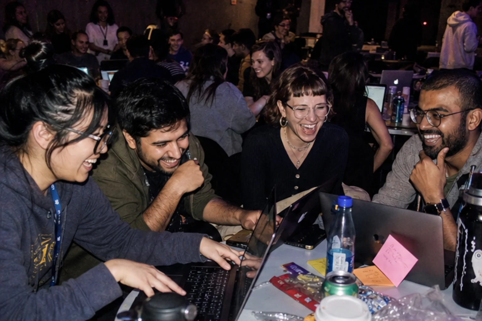Builders crowding around laptops at a shared table